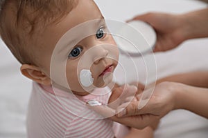 Mother applying moisturizing cream on her baby, closeup