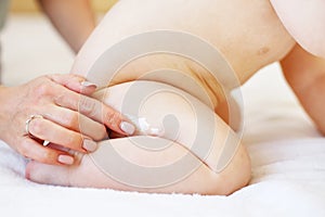Mother applying some cream by her hand to the baby ass for skin care.