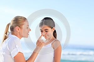 Mother applying sun cream on her daugter's nose