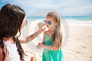 Mother applying sunblock cream on her child nose