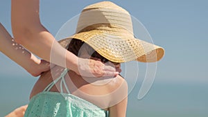 Mother applying sunblock cream on her daughters shoulder. Sun protection of childs skin.