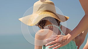 Mother applying sunblock cream on her daughters shoulder. Sun protection of childs skin.