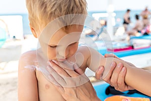 Mother applying sunscreen protection creme on cute little baby boy kid face. Mum using sunblocking lotion to protect