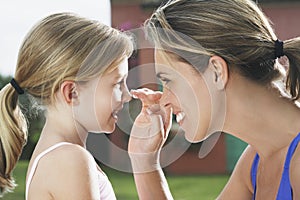 Mother Applying Sunscreen To Girl's Nose