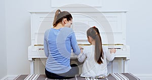 Mother assisting daughter in playing piano 4k