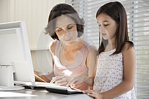 Mother Assisting Daughter In Using Computer And Calculator