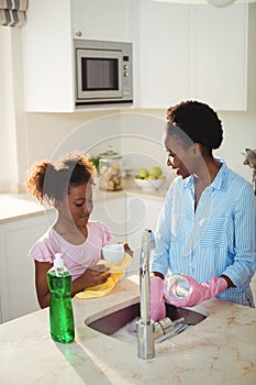 Mother assisting her daughter in cleaning utensils