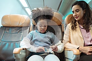 mother assists her youngster in fastening his seatbelt to keep him safe during a flight