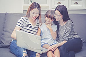 Mother, Aunt and kid having time together lerning with using laptop computer at home