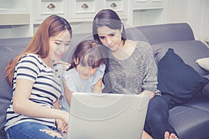 Mother, Aunt and kid having time together lerning with using laptop computer at home with relax and happy