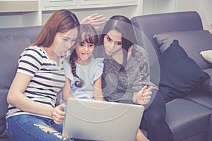 Mother, Aunt and kid having time together lerning with using laptop computer at home with relax and happy