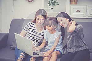 Mother, Aunt and kid having time together lerning with using laptop computer at home with relax and happy on couch