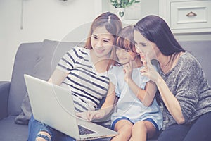 Mother, Aunt and kid having time together lerning with using laptop computer at home with relax and happy on couch