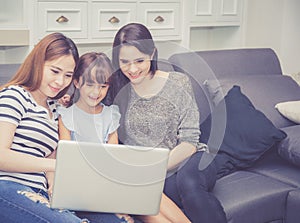 Mother, Aunt and kid having time together lerning with using laptop computer at home photo