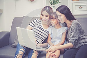 Mother, Aunt and kid having time together lerning with using laptop computer at home with relax and happy on couch photo