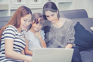 Mother, Aunt and kid having time together lerning with using laptop computer at home with relax and happy photo