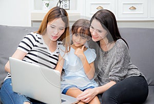 Mother, Aunt and kid having time together lerning with using laptop at home on couch, family concept. photo