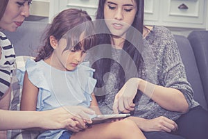 Mother, Aunt and kid having time together lerning with using tablet at home with relax and happy on couch