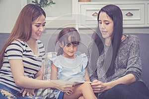 Mother, Aunt and kid having time together lerning with using tablet at home with relax and happy on couch