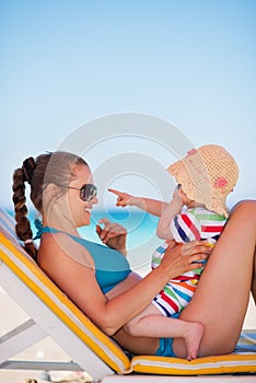 Mother with baby on beach playing with sunglasses