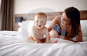 Mother and baby in bed. Young mom playing with her son. Child an