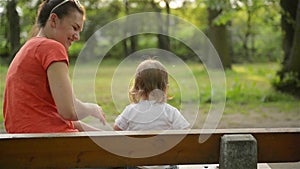 Mother and baby blowing on a dandelion on the nature in the summer in the park