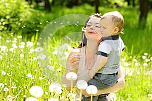 Mother and baby boy blowing on a dandelion