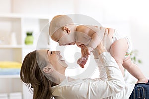 Mother and baby boy in diaper playing in sunny room. Parent and little kid relaxing at home. Family having fun together. photo