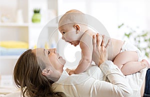 Mother and baby boy in diaper playing in sunny room. Parent and little kid relaxing at home. Family having fun together.