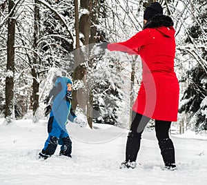 Mother with baby boy playing in snowy winter forest