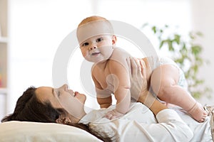 Mother and baby boy playing in sunny bedroom. Parent and little kid relaxing at home. Family having fun together.