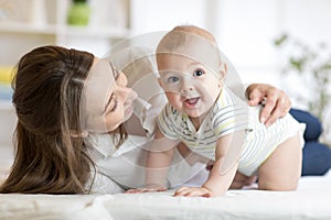 Mother and baby boy playing in sunny bedroom. Parent and little kid relaxing at home. Family having fun together.