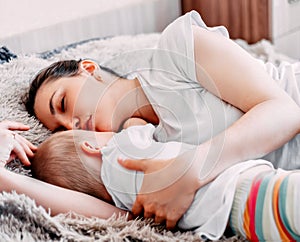 mother and baby boy sleeping together on bed