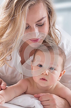 Mother and baby boy son playing on a white bed. Mothers tenderness and kisses of a toddler child