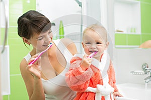 Mother with baby brushing teeth in bathroom