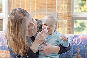 Mother at baby care giving her baby a nasal spray for colds