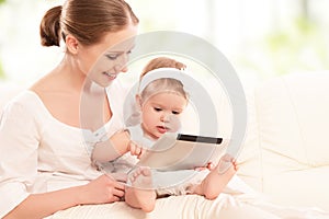 Mother and baby child with tablet computer on the couch at home