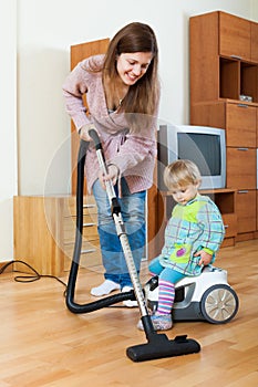 Mother with a baby cleaning in the house