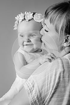 Mother and baby daughter plays, hugging, kissing at hom