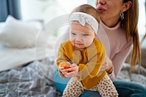 Mother and baby daughter plays, hugging, kissing at home. Happy family.