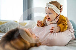 Mother and baby daughter plays, hugging, kissing at home. Happy family.