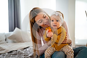 Mother and baby daughter plays, hugging, kissing at home. Happy family.