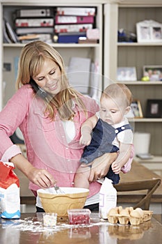 Mother And Baby Daughter Preparing Ingredients To Bake Cakes In Kitchen