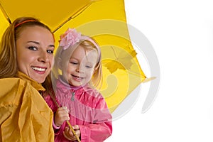 Mother and baby daughter under yellow umbrella