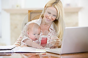 Mother and baby in dining room with laptop