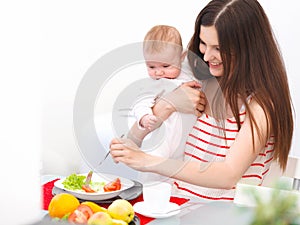 Mother and Baby eating at Home. Happy Smiling Family Portrait