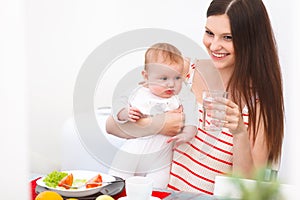 Mother and Baby eating at Home. Happy Smiling Family Portrait