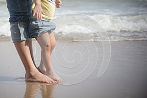 Mother and baby feet on sand summer beach. Family insurance support concept