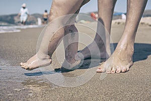 Mother and baby feet walking on sand beach