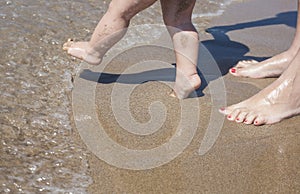 Mother and baby feet walking on sand beach